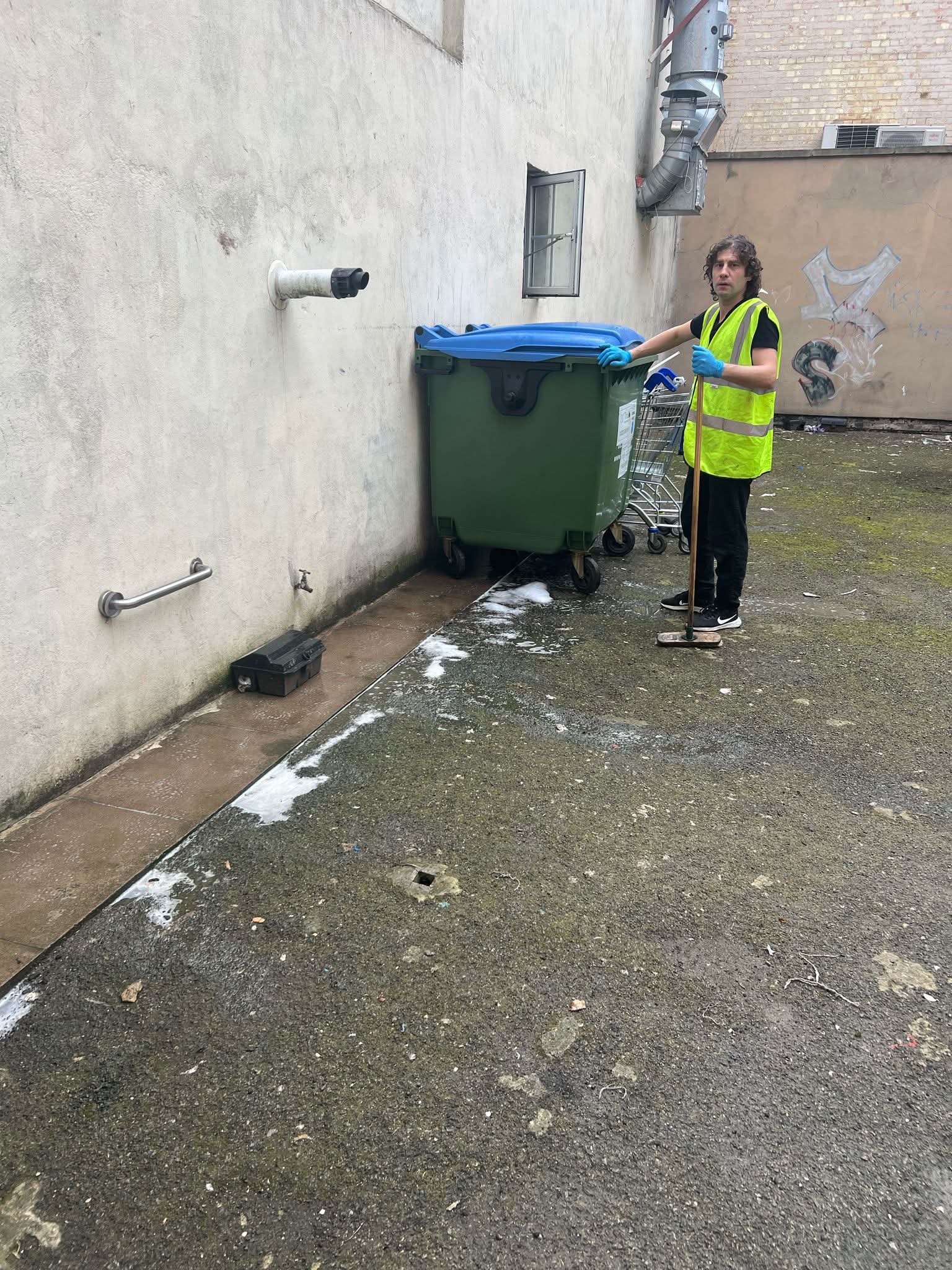 Cleaning around the bin area in a business courtyard