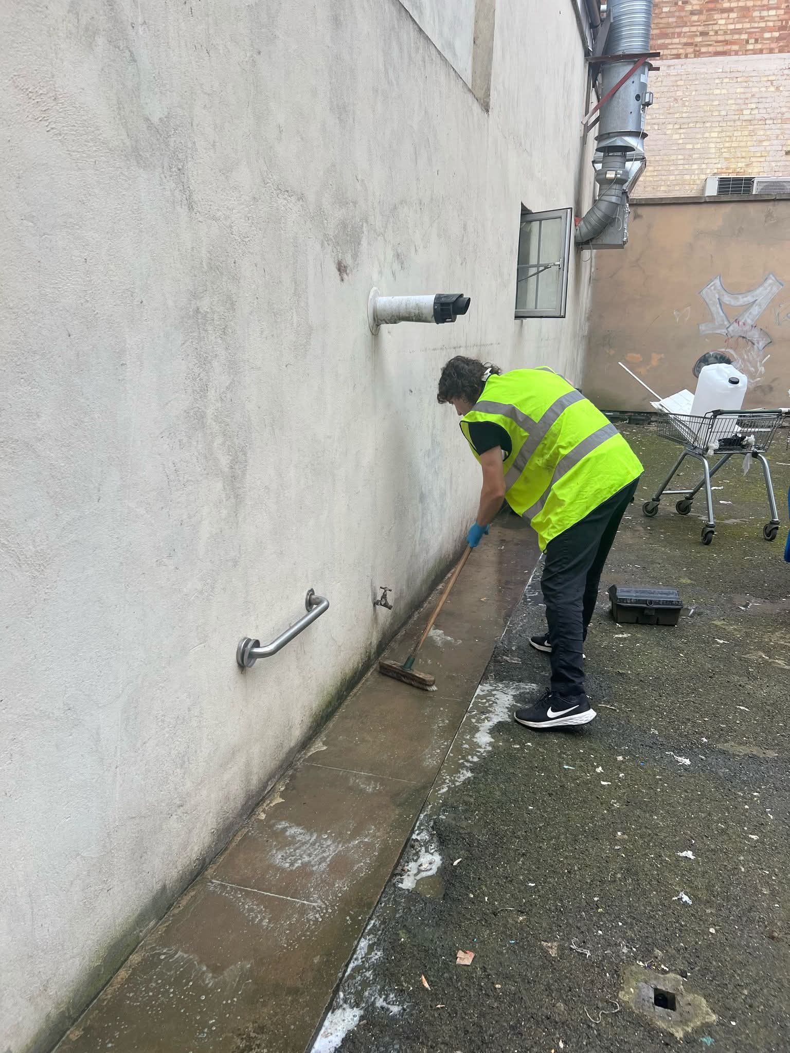 Scrubbing a courtyard path with a brush