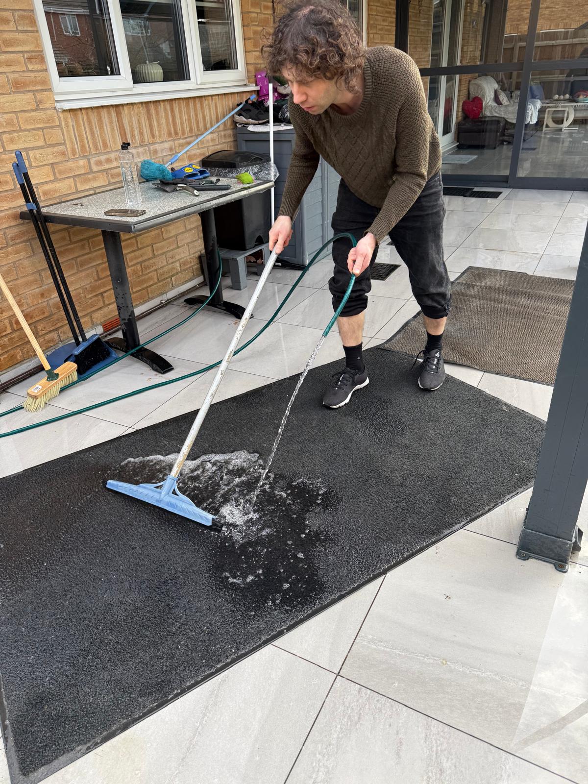 Washing a rug with water and a brush on a patio